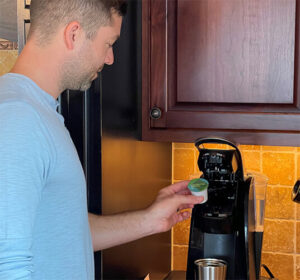 man placing compostable k-cup into keurig machine